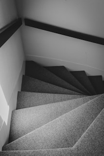 Stairs with carpet winding upwards in black and white.