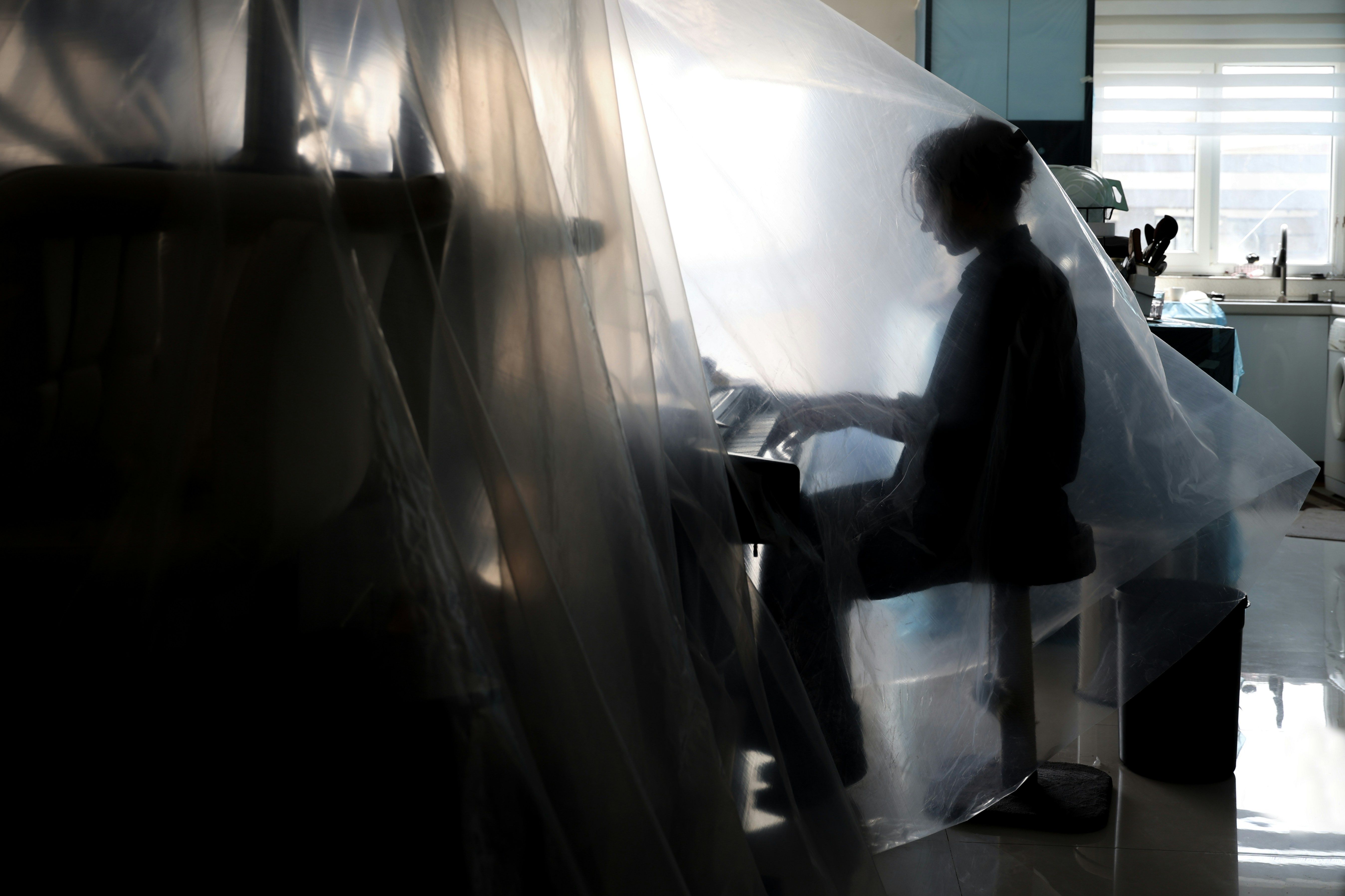 A person sits under plastic sheeting.