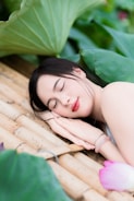 A woman rests peacefully among lotus leaves.
