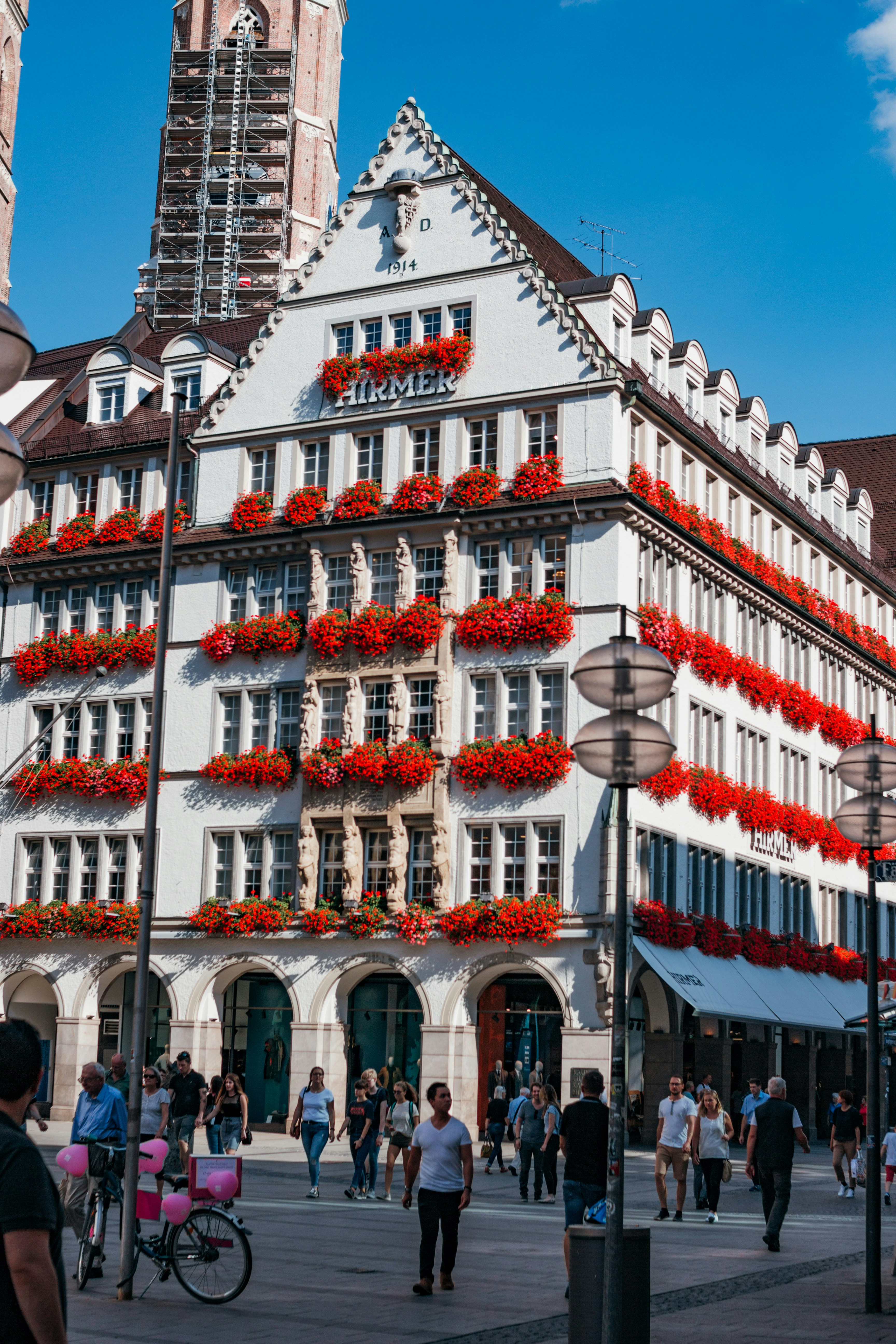 Un bellissimo edificio con fiori rossi e molte persone.
