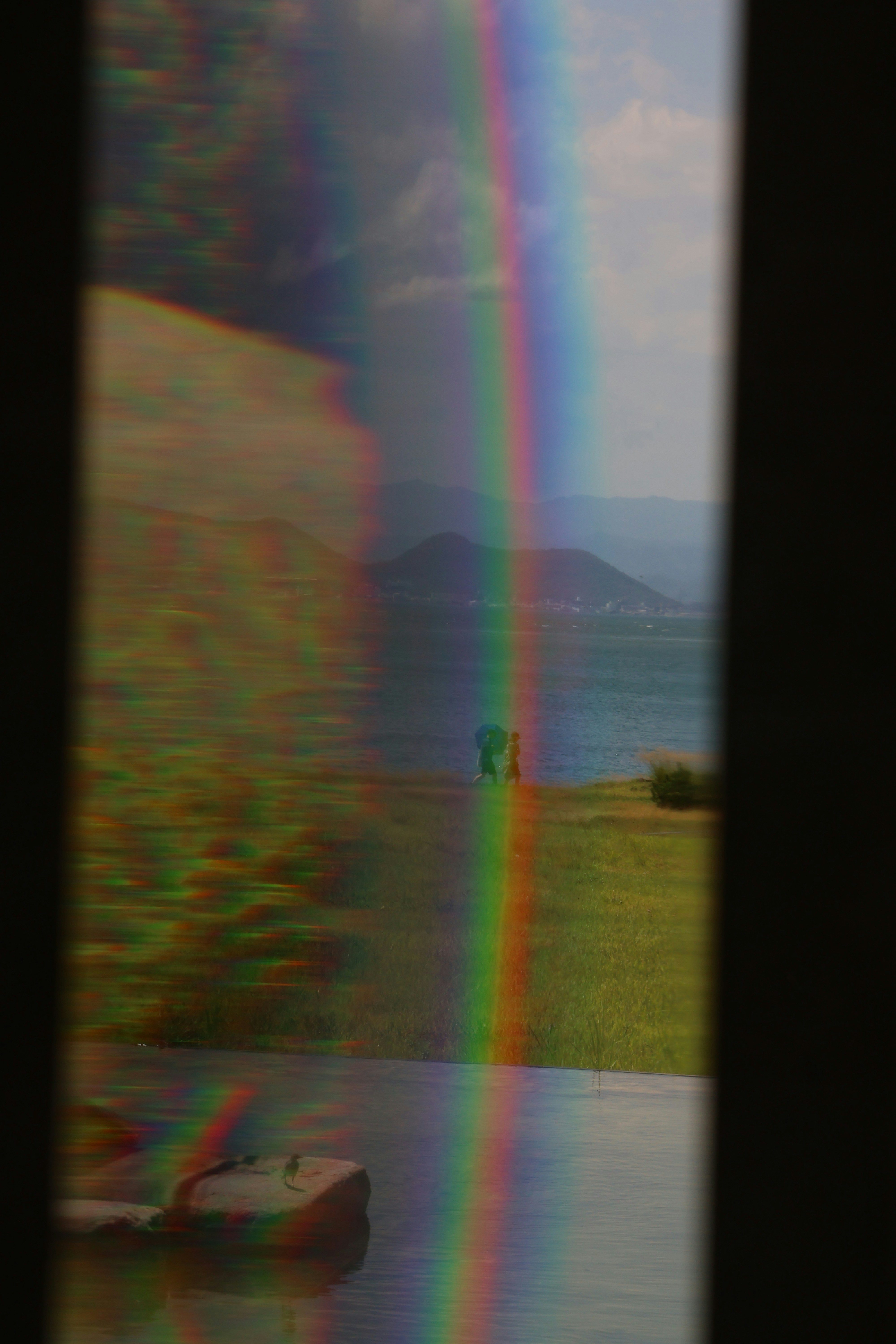 A rainbow arches over water and land.