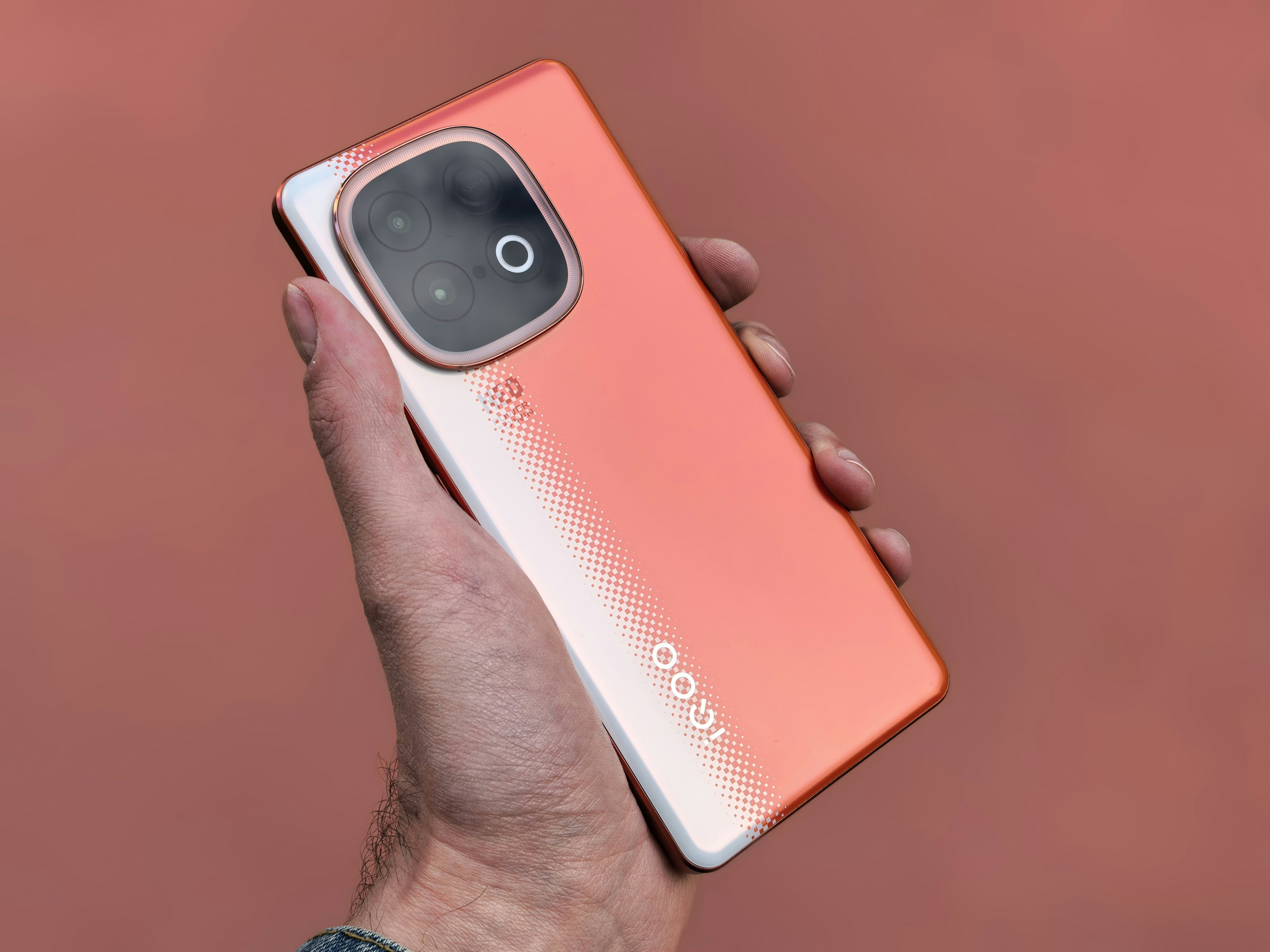 A person holds a unique, orange smartphone.