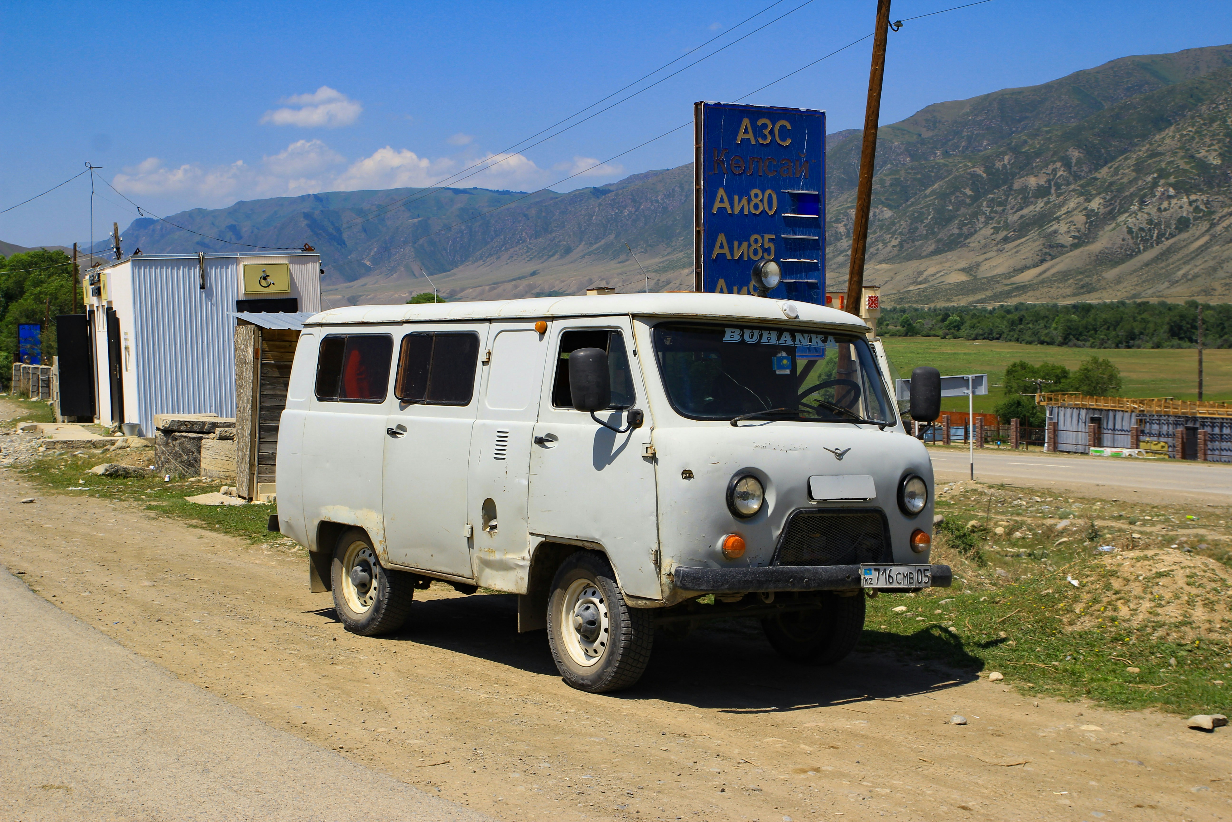 An old white van sits near a roadside gas station.