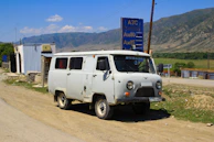 An old white van sits near a roadside gas station.