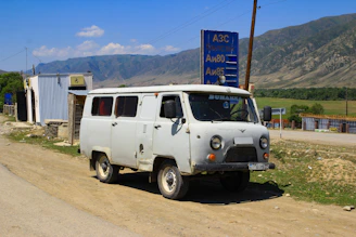 An old white van sits near a roadside gas station.