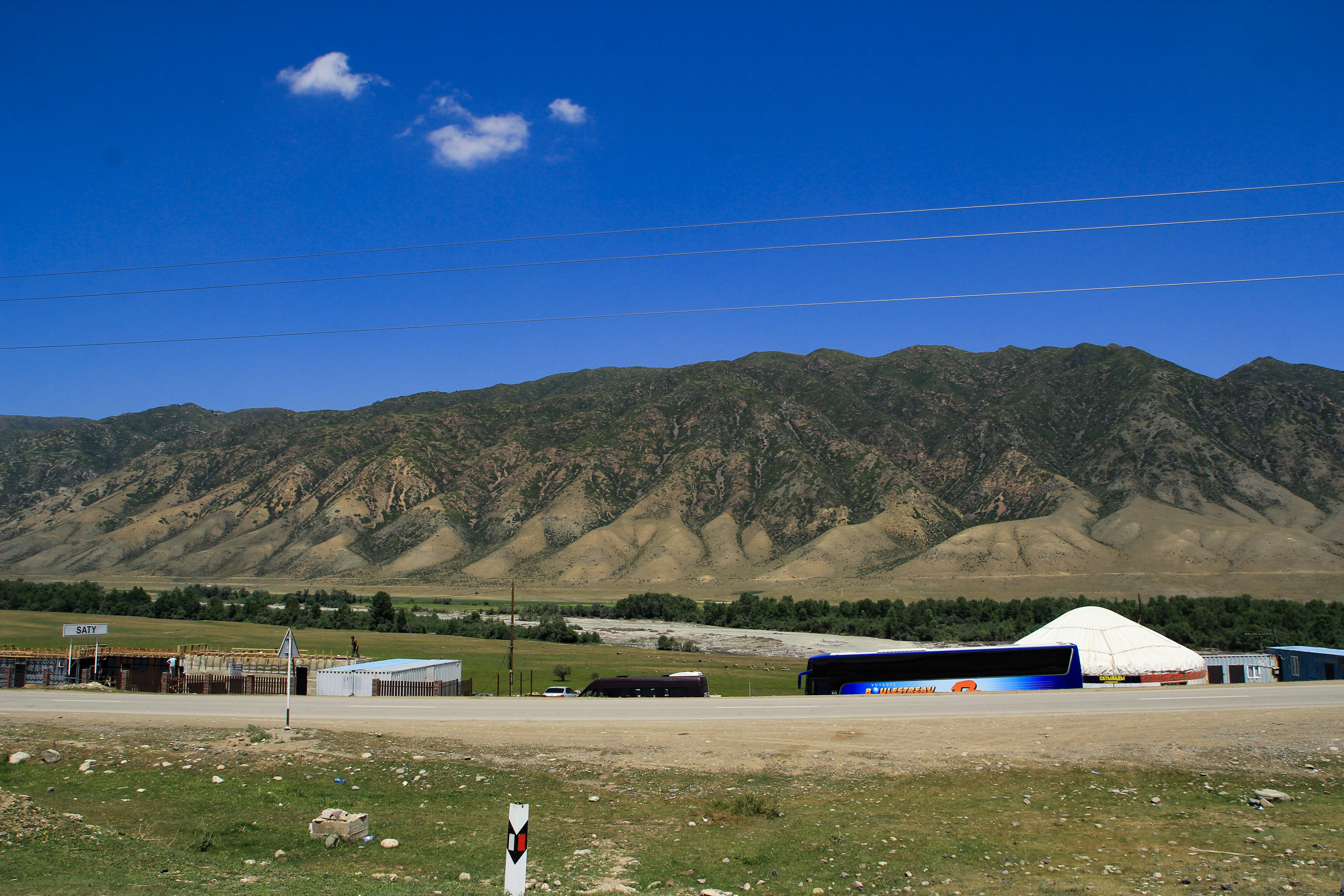 Mountains and buildings stand under a blue sky.