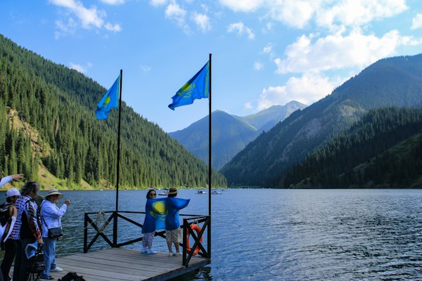 People wave kazakh flags by a beautiful lake — Kolsay Lakes, Kazakhstan