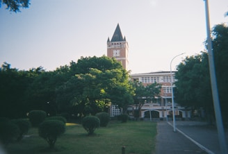 A clock tower looms over a lush green campus.