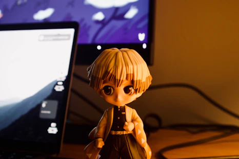 Zenitsu figure in front of a laptop and monitor.