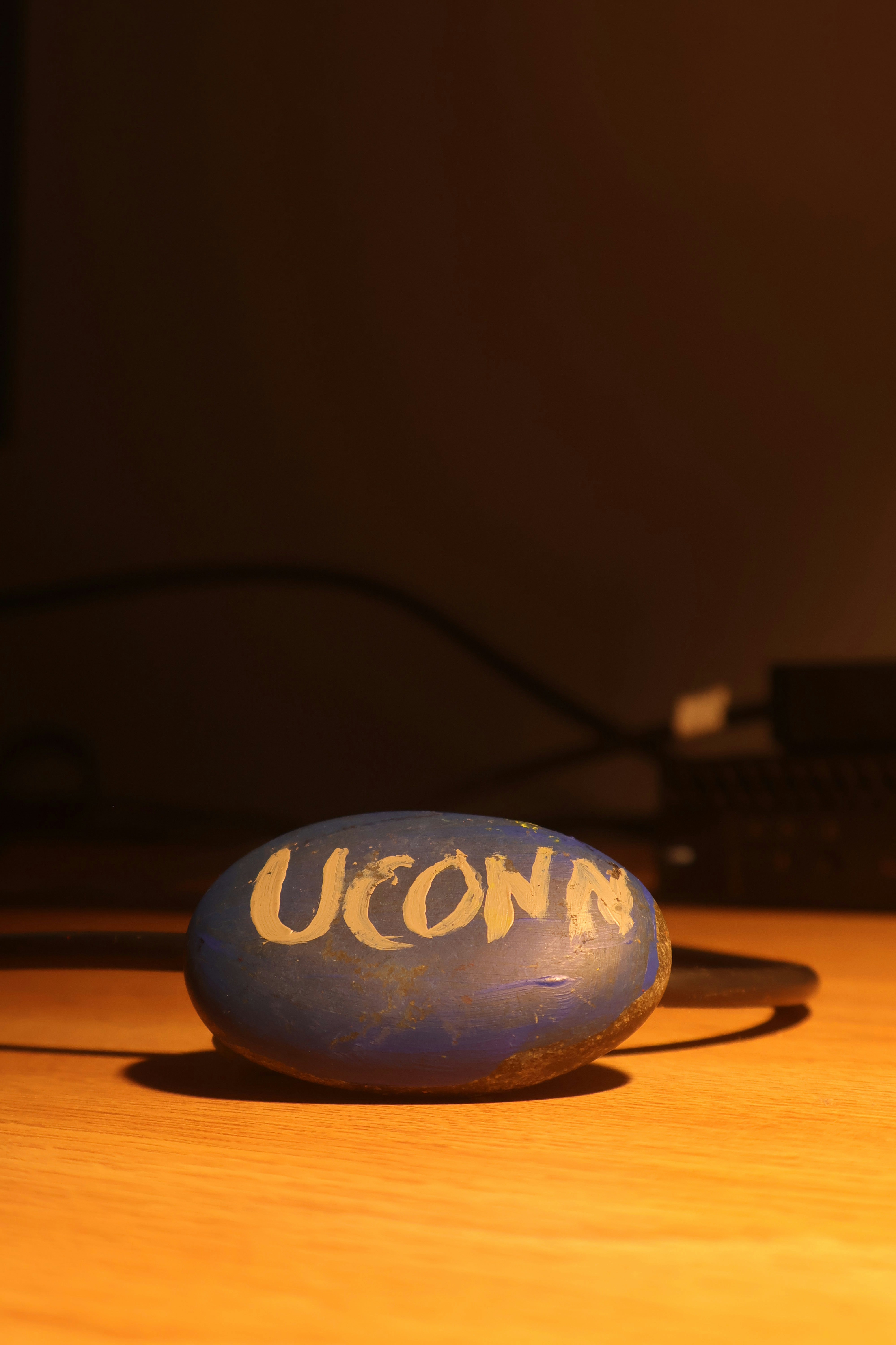 A blue stone reads "uconn" on a wood surface.