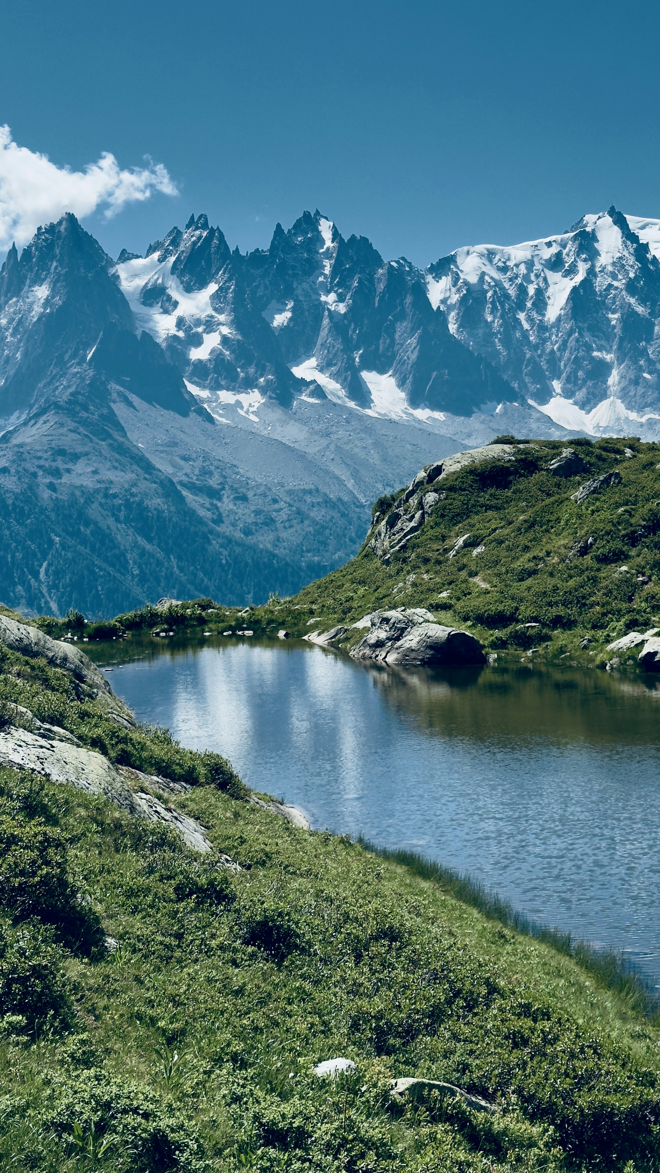 Mountains reflect in a calm lake under a blue sky.