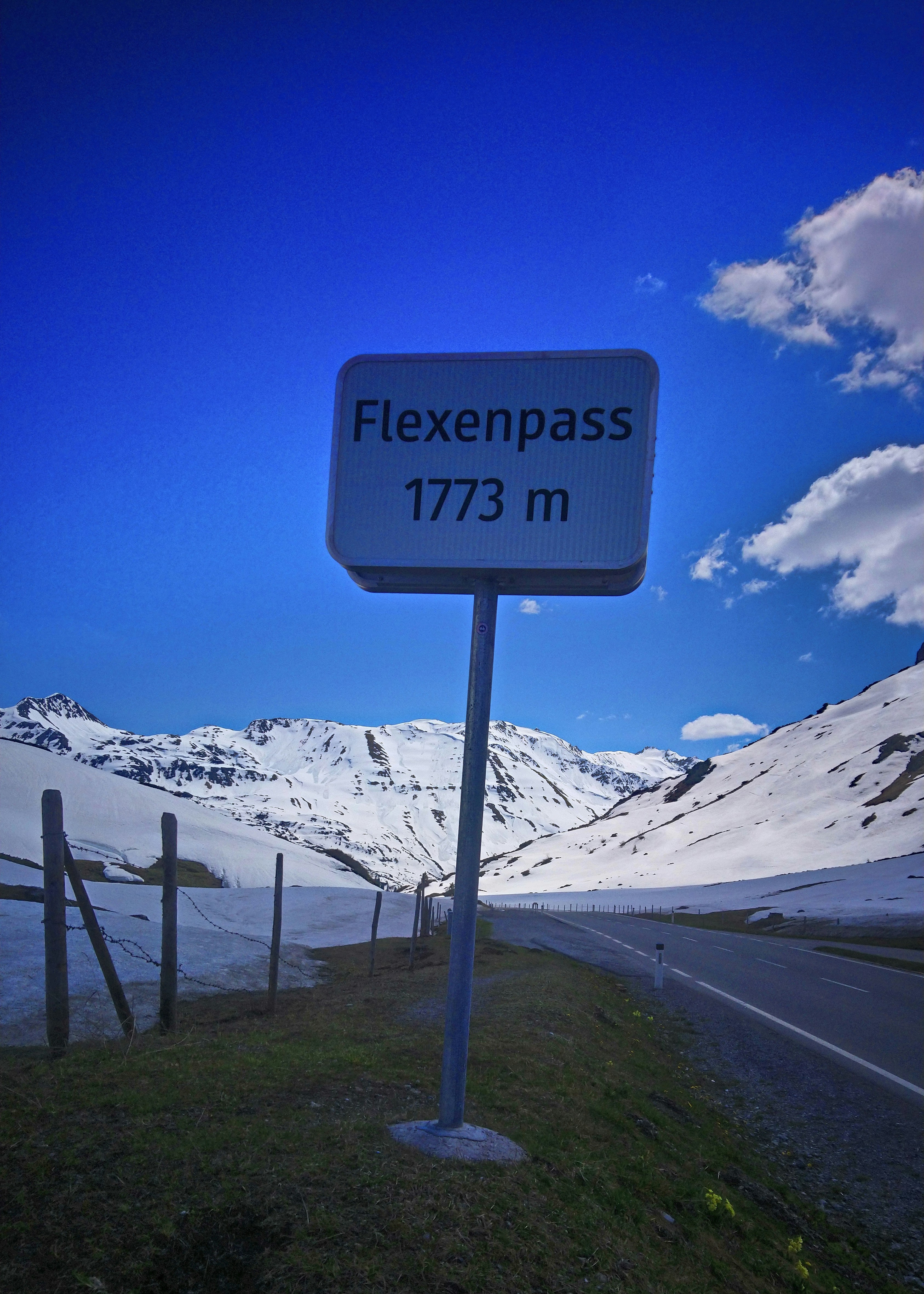 Flexenpass mountain pass sign with snowy mountains.