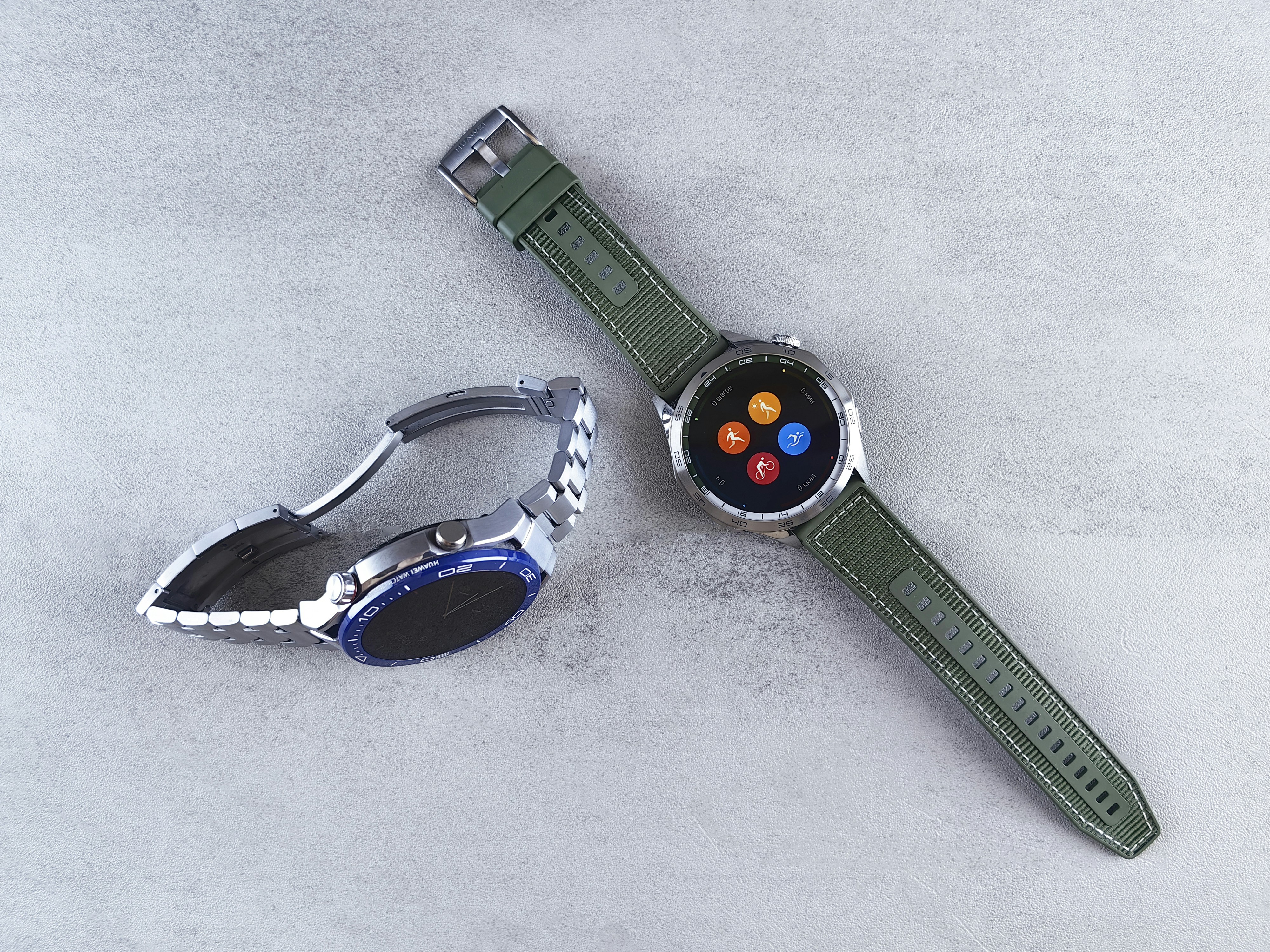 Two modern smartwatches are displayed on a surface.