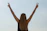 Woman celebrates with a peace sign against the sky.