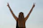 Woman celebrates with a peace sign against the sky.