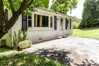 A small white house with a shaded driveway.