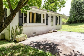 A small white house with a shaded driveway.