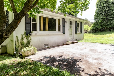A small white house with a shaded driveway.