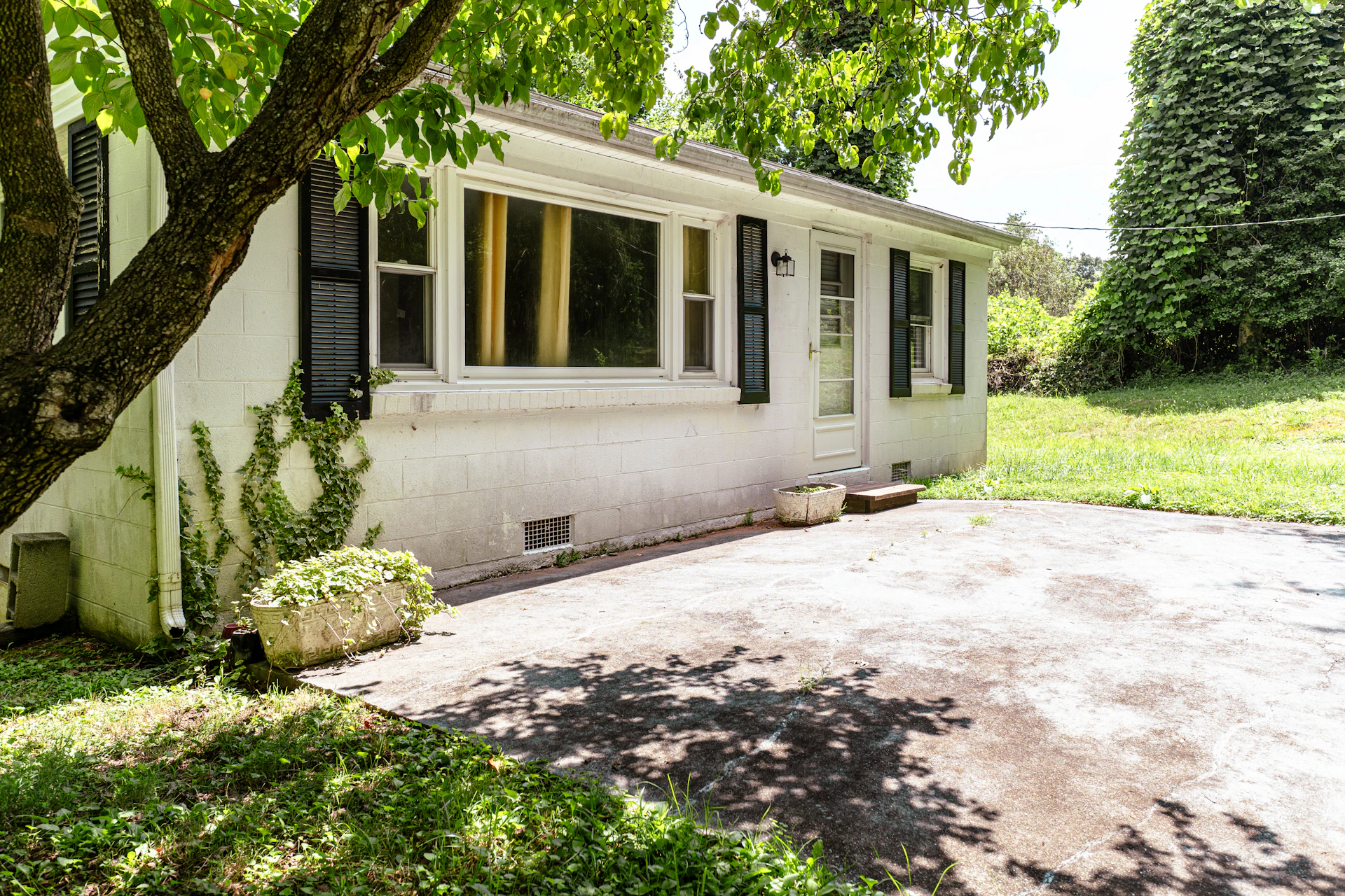 A small white house with a shaded driveway
