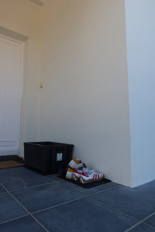 Shoes and a shoebox left on the floor beside a doorway.