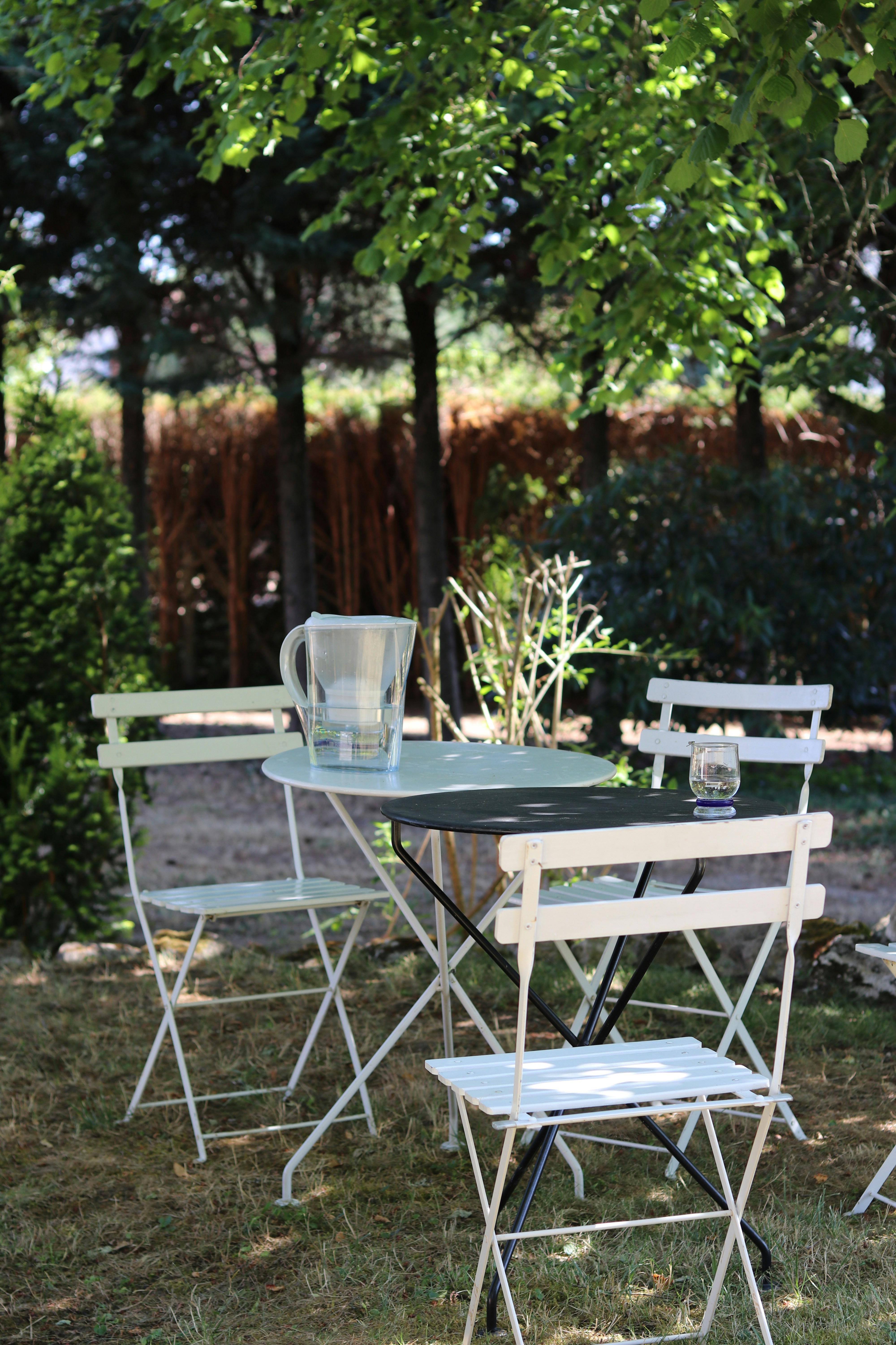 A table and chairs sit outdoors under trees.