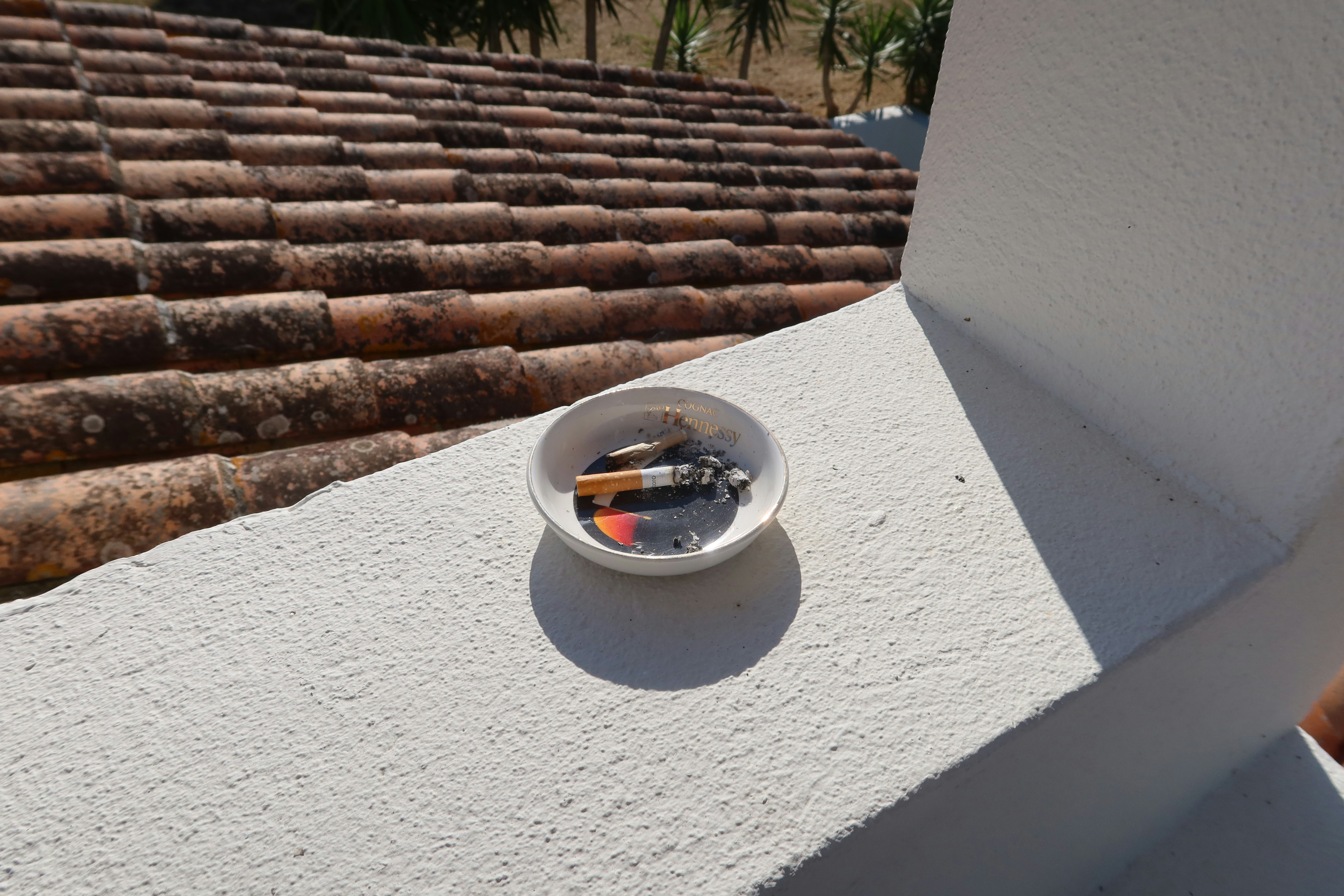 Ashtray on a ledge filled with cigarette butts.
