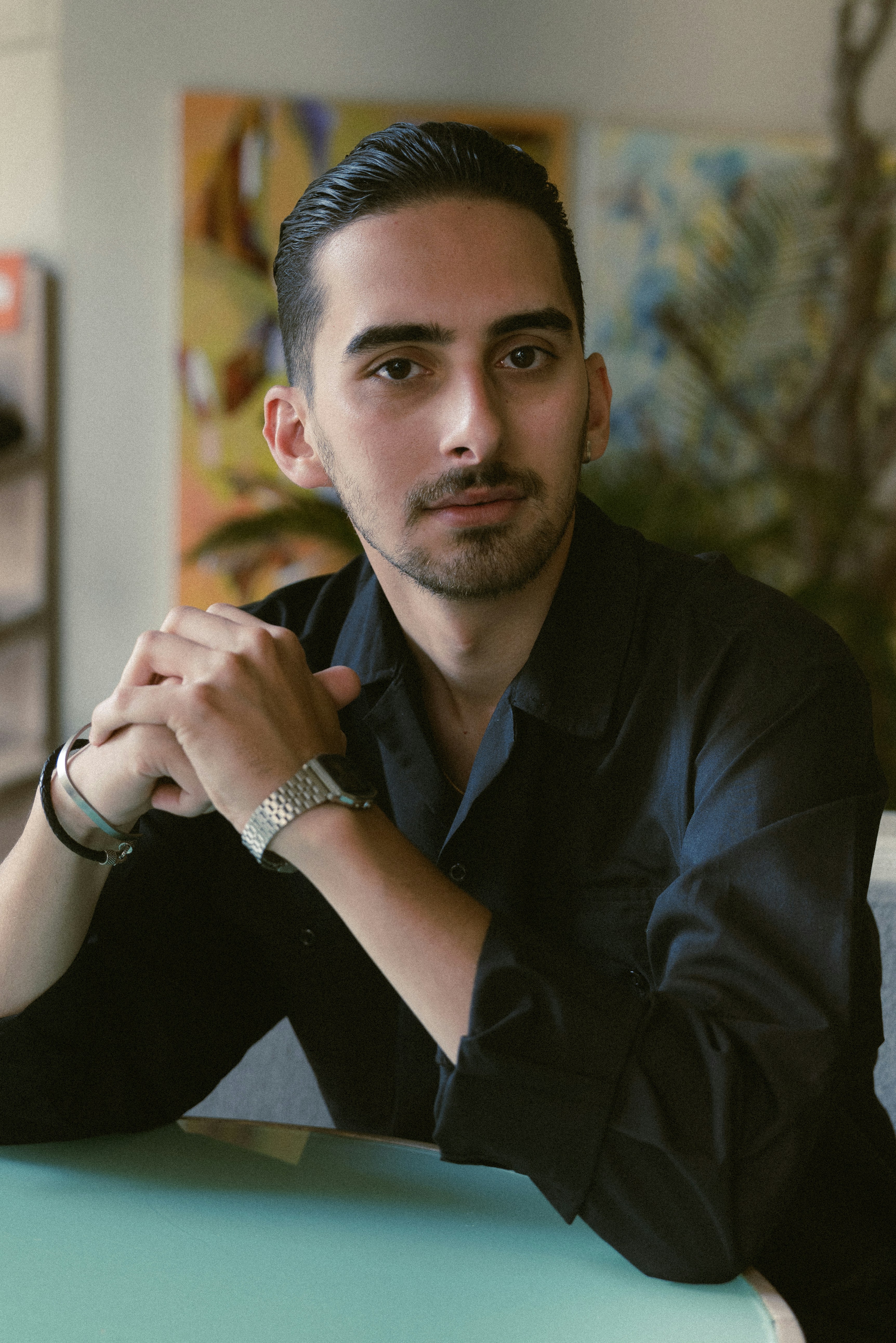 A confident man is seated and looking at the camera.