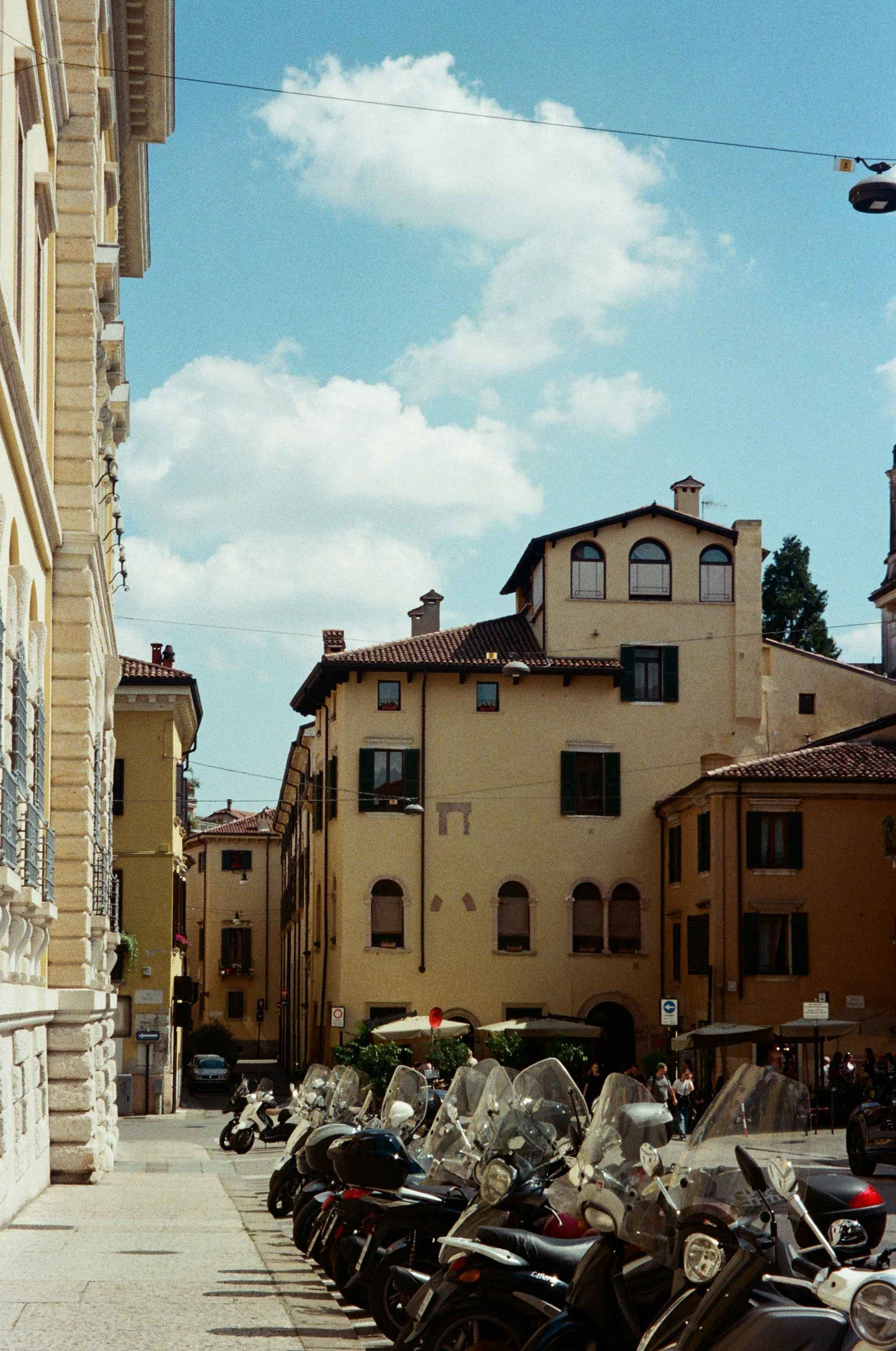 Los edificios se alinean en una calle con scooters bajo un cielo azul.