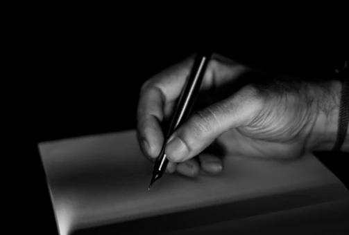 A hand writing with a pen on paper.