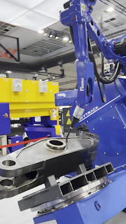 A robot arm works on a metal piece.