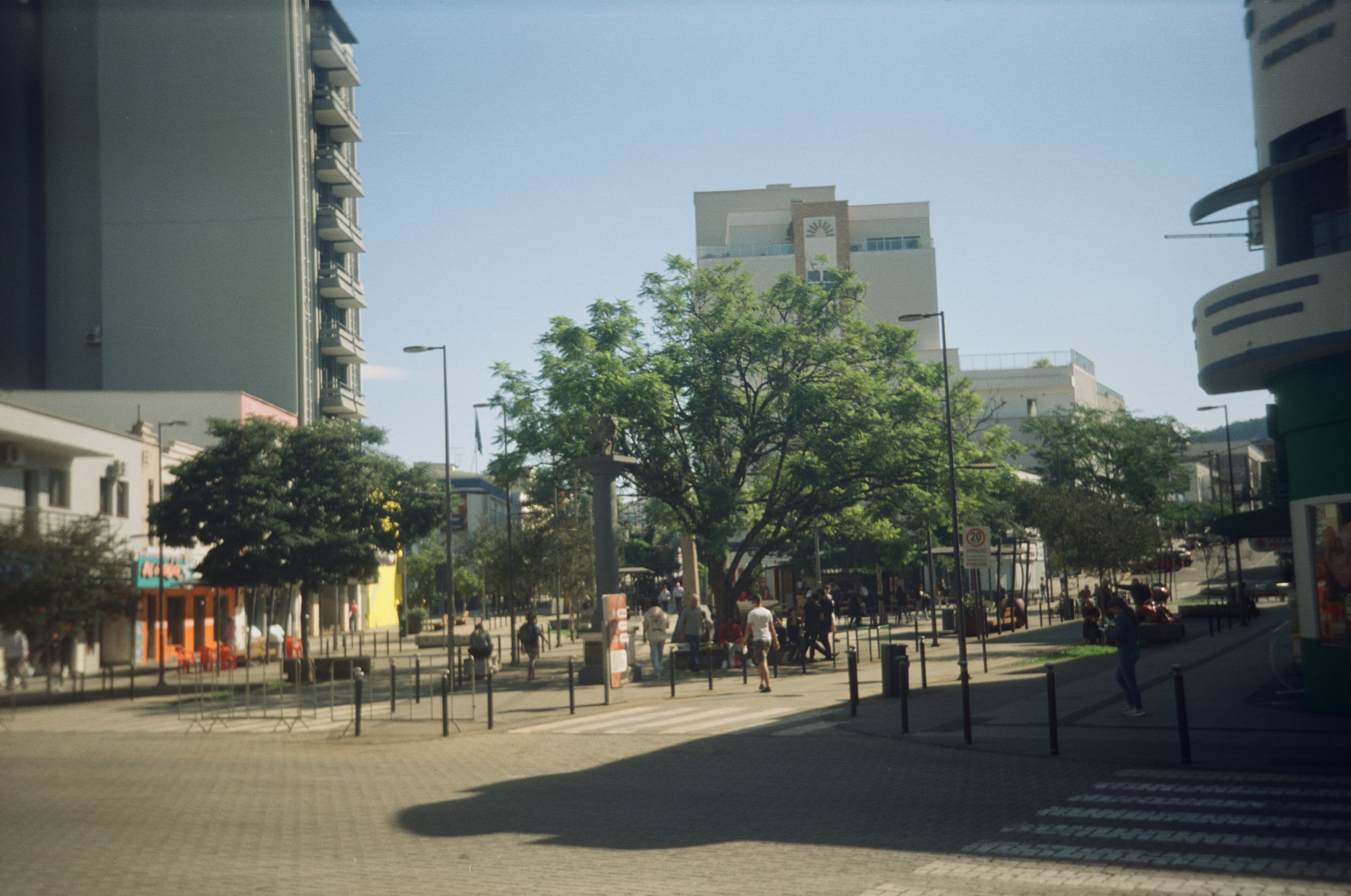 An urban park scene with buildings and people.