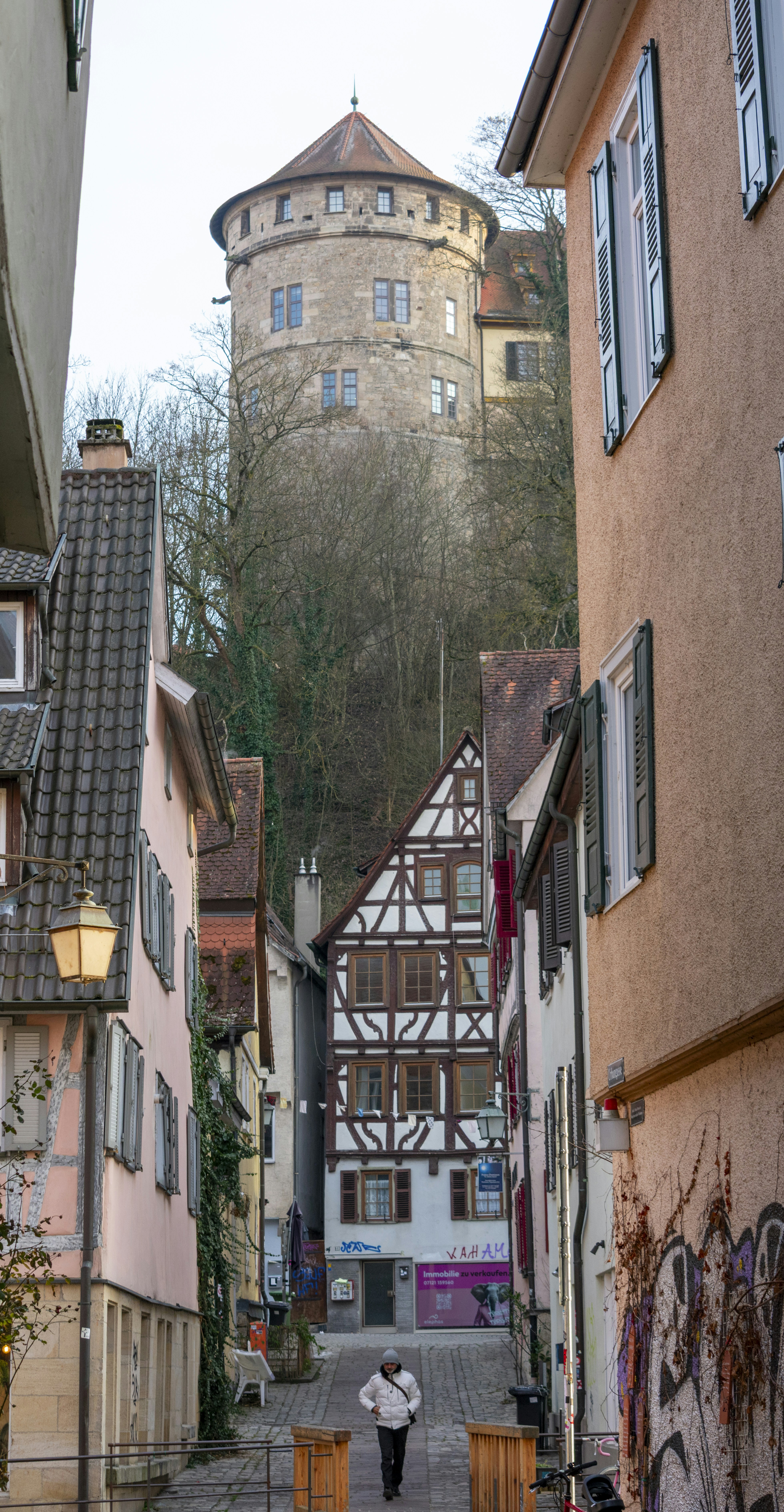 A narrow street leads to a stone tower.