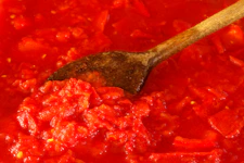 Tomato sauce being stirred with a wooden spoon.
