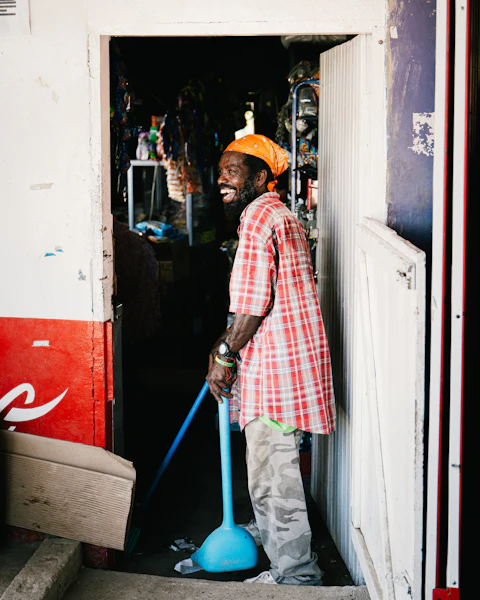 A smiling man sweeping inside a doorway