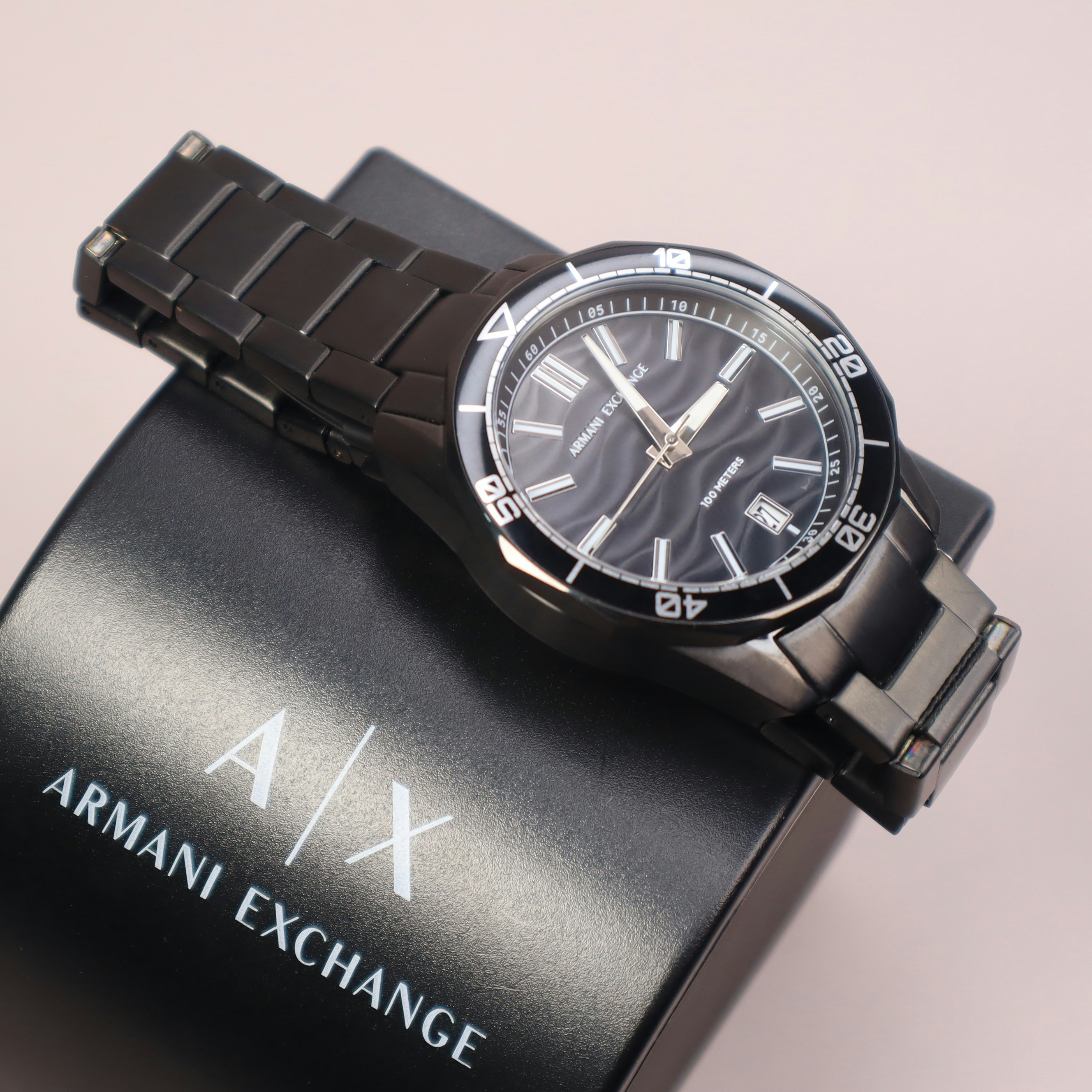 A black armani exchange watch sits on a box.