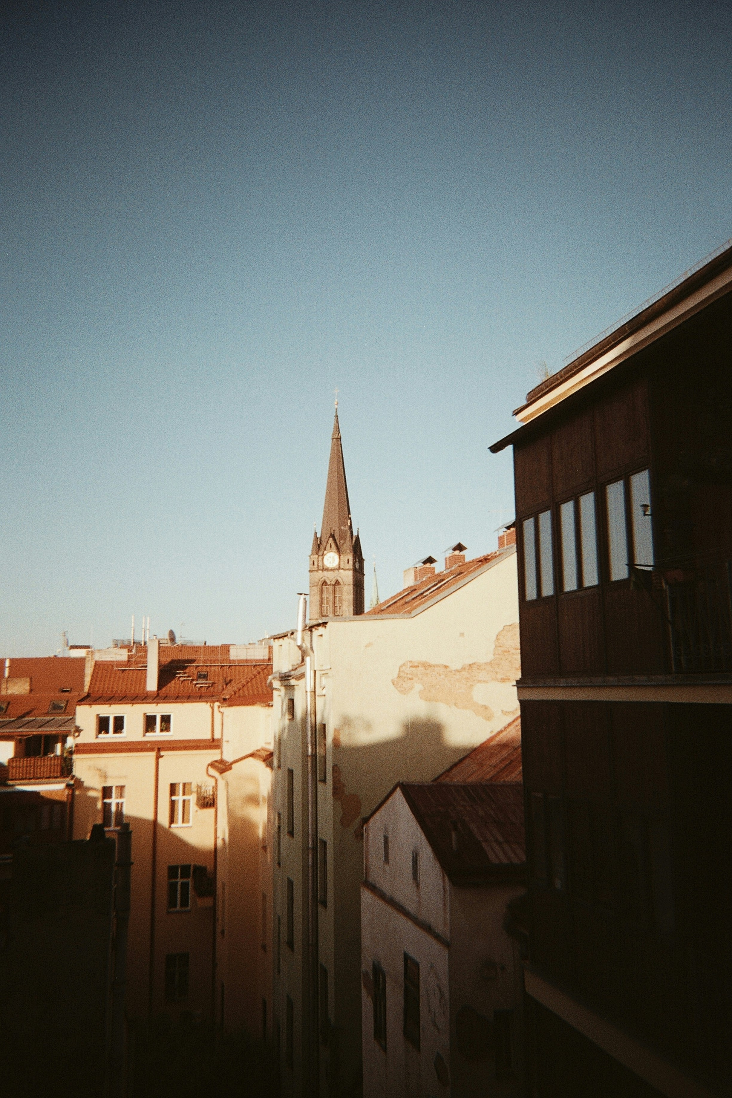 Buildings and a church steeple against a blue sky.