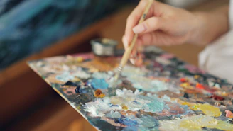 Artist mixing paints on a colorful palette.