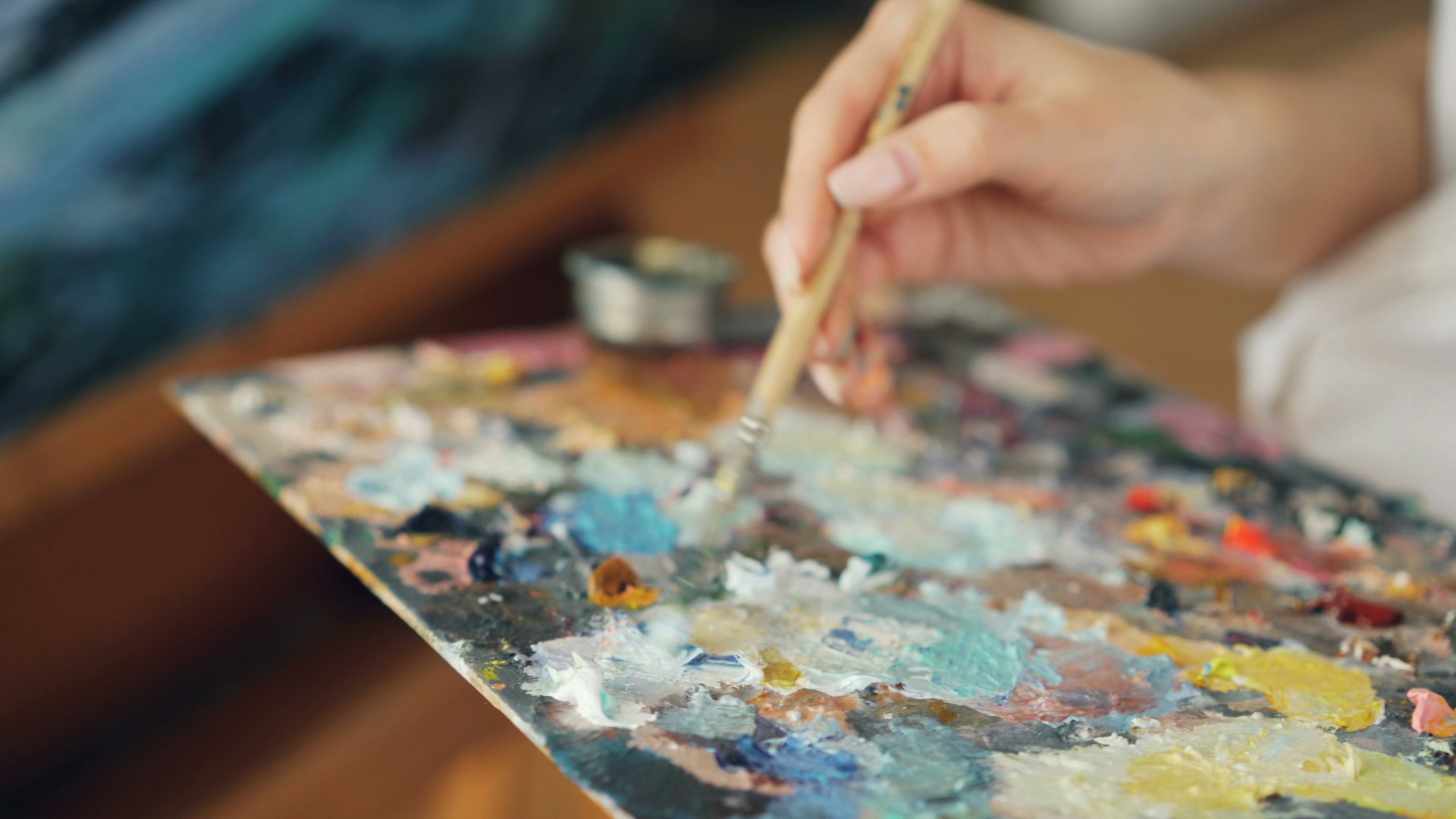 Artist mixing paints on a colorful palette.