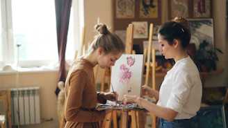 Two women paint together in an art studio.