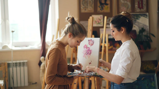 Two women paint together in an art studio.