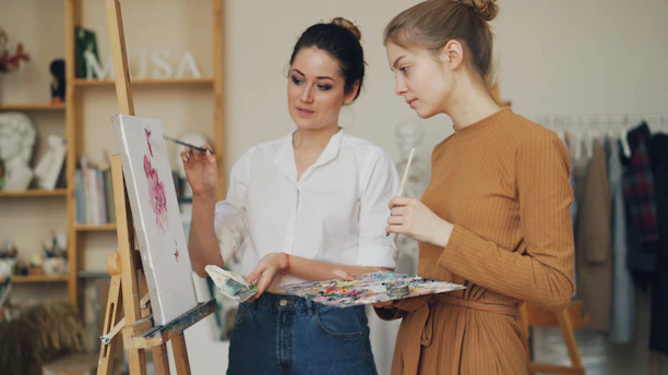 Two women are painting and discussing art.