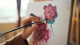 An artist paints flowers on a canvas.