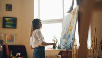 A woman paints a picture in a sunny studio.