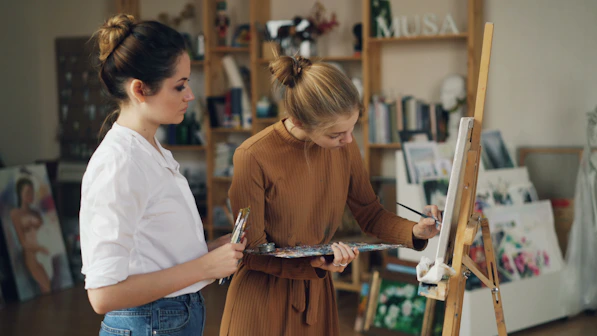 Two women are painting in an art studio.