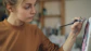 Young woman carefully paints on a canvas.