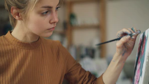 Young woman carefully paints on a canvas