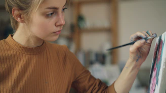 Young woman carefully paints on a canvas