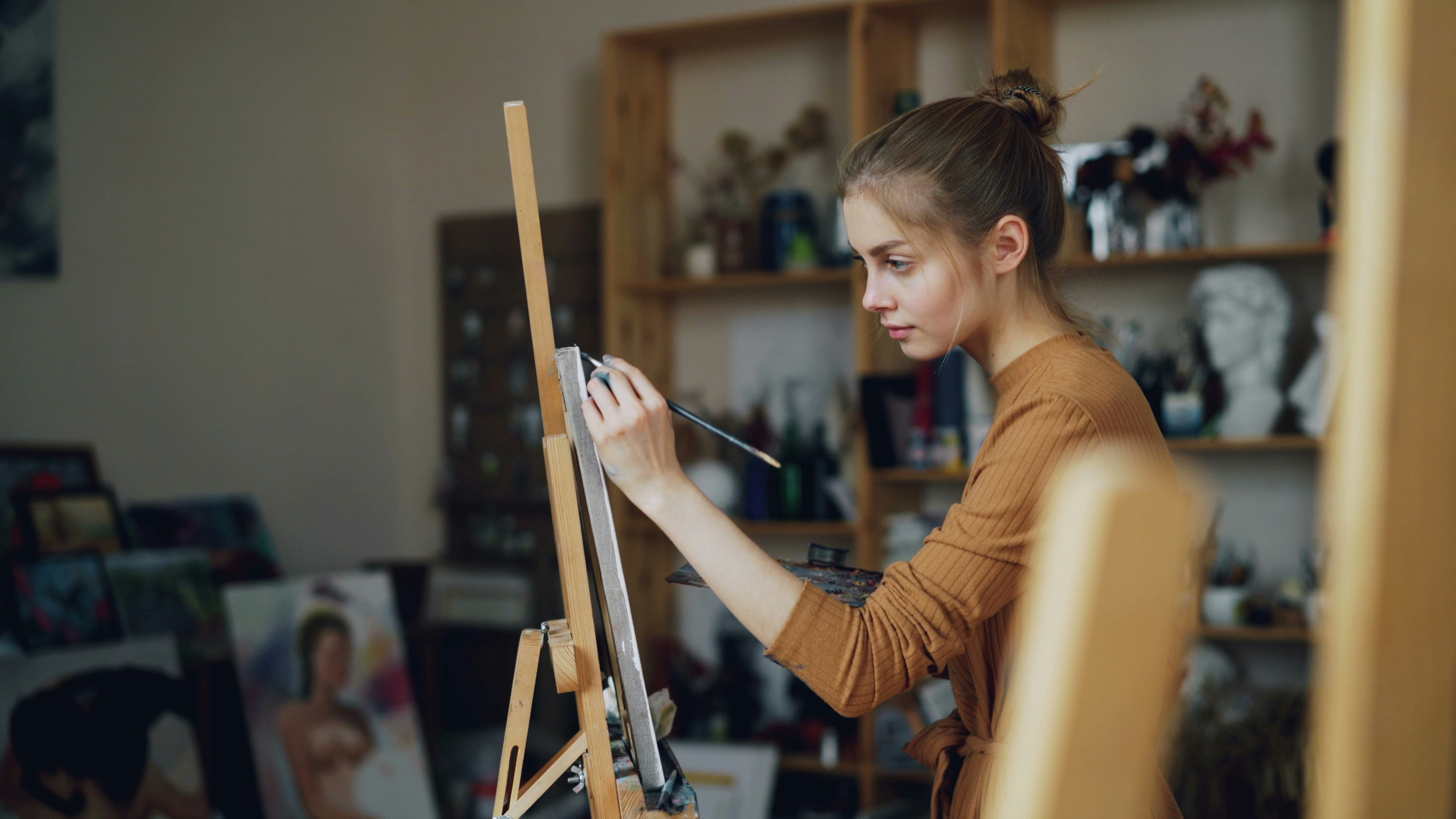 A young woman paints in her art studio.