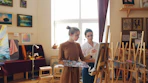 Two women are painting in an art studio.