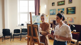 Two women paint together in an art studio.